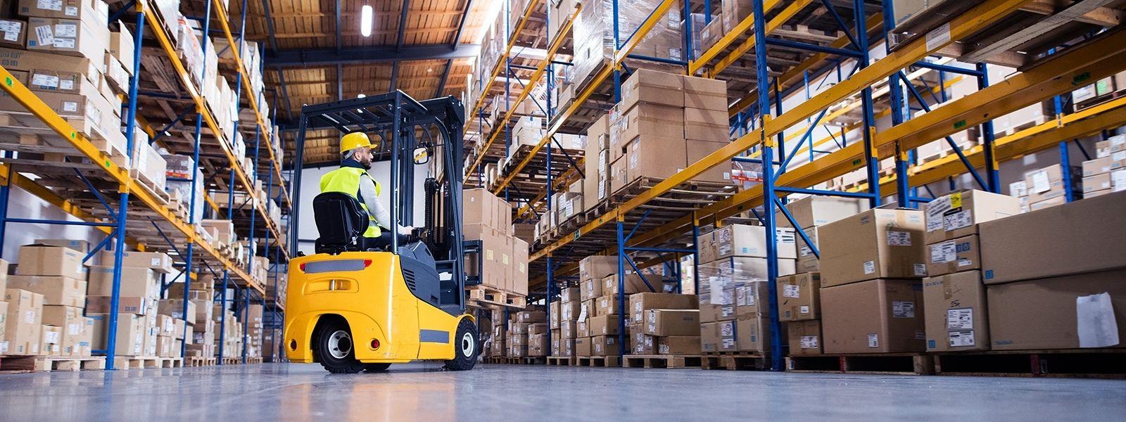 man in forklift in warehouse with racks filled with boxes