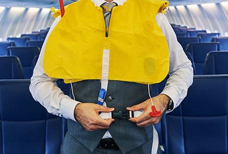 Flight attendant demonstrating life vest on aircraft