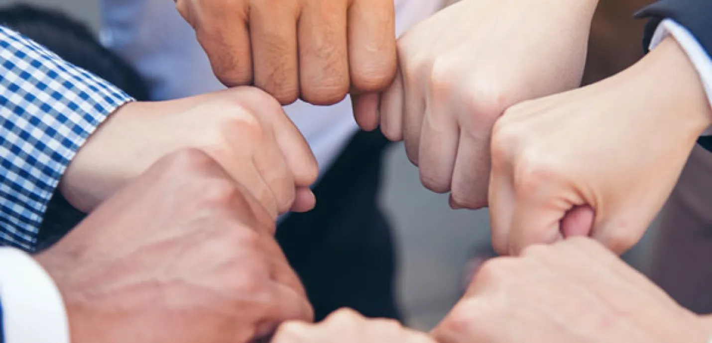 Several people standing in a circle bumping fists