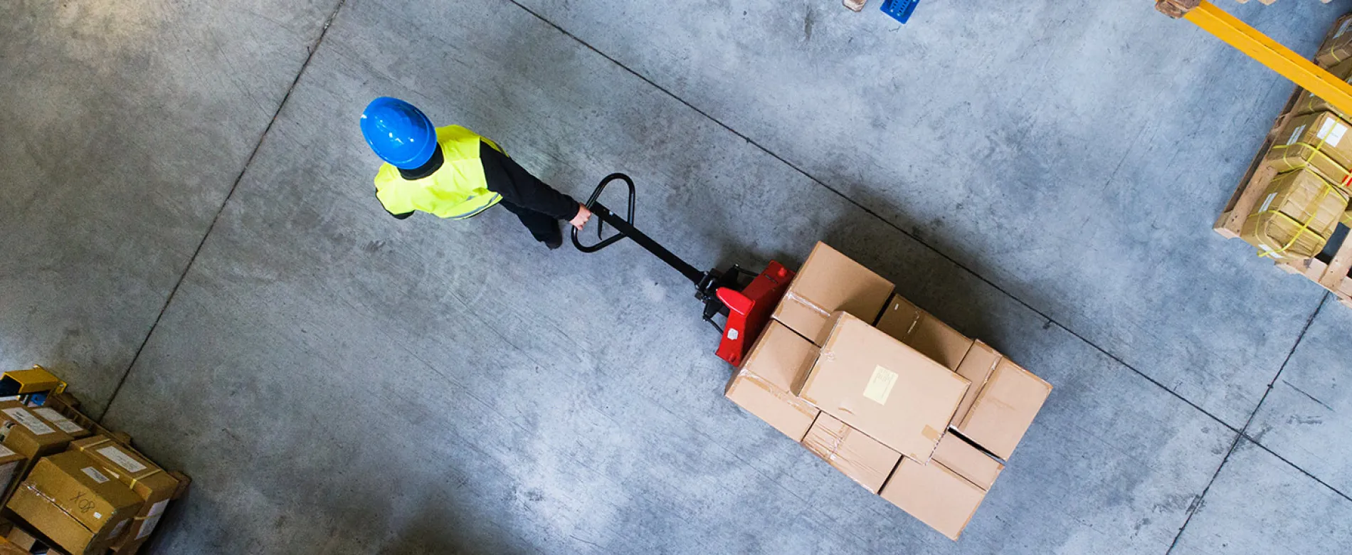 Man pulling pallet truck through warehouse
