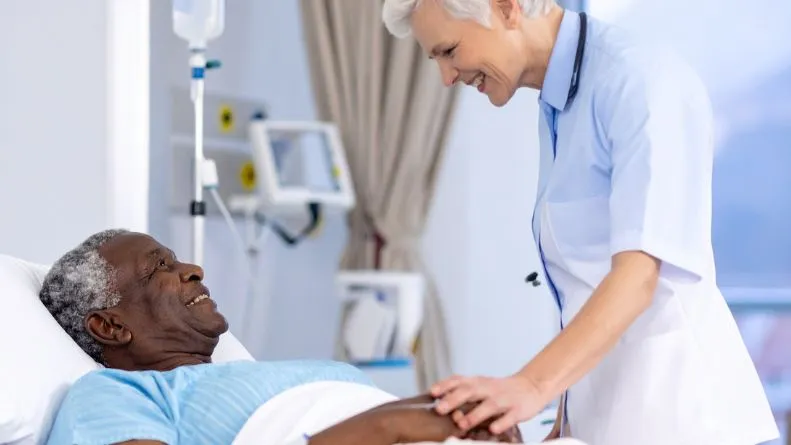 Nurse looking after patient in hospital bed, protected by contact tracing solution by RFiD Discovery