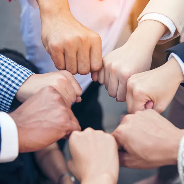 Several people standing in a circle bumping fists